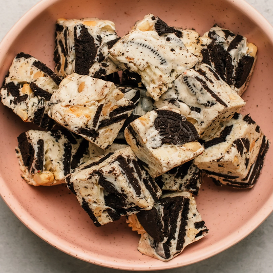 Creamy Oreo fudge squares with crushed cookies and peanuts in a pink bowl